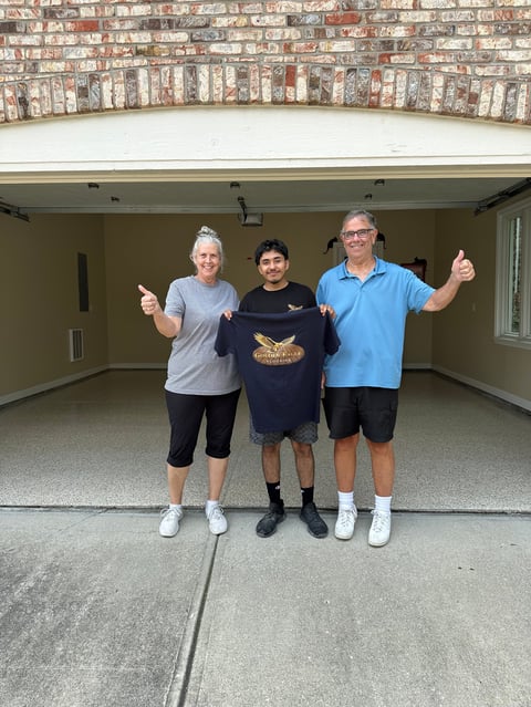 Three people standing in a garage with thumbs up, smiling at the camera